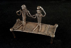 Figurine représentant un couple assis sur un lit de cordes tressées
